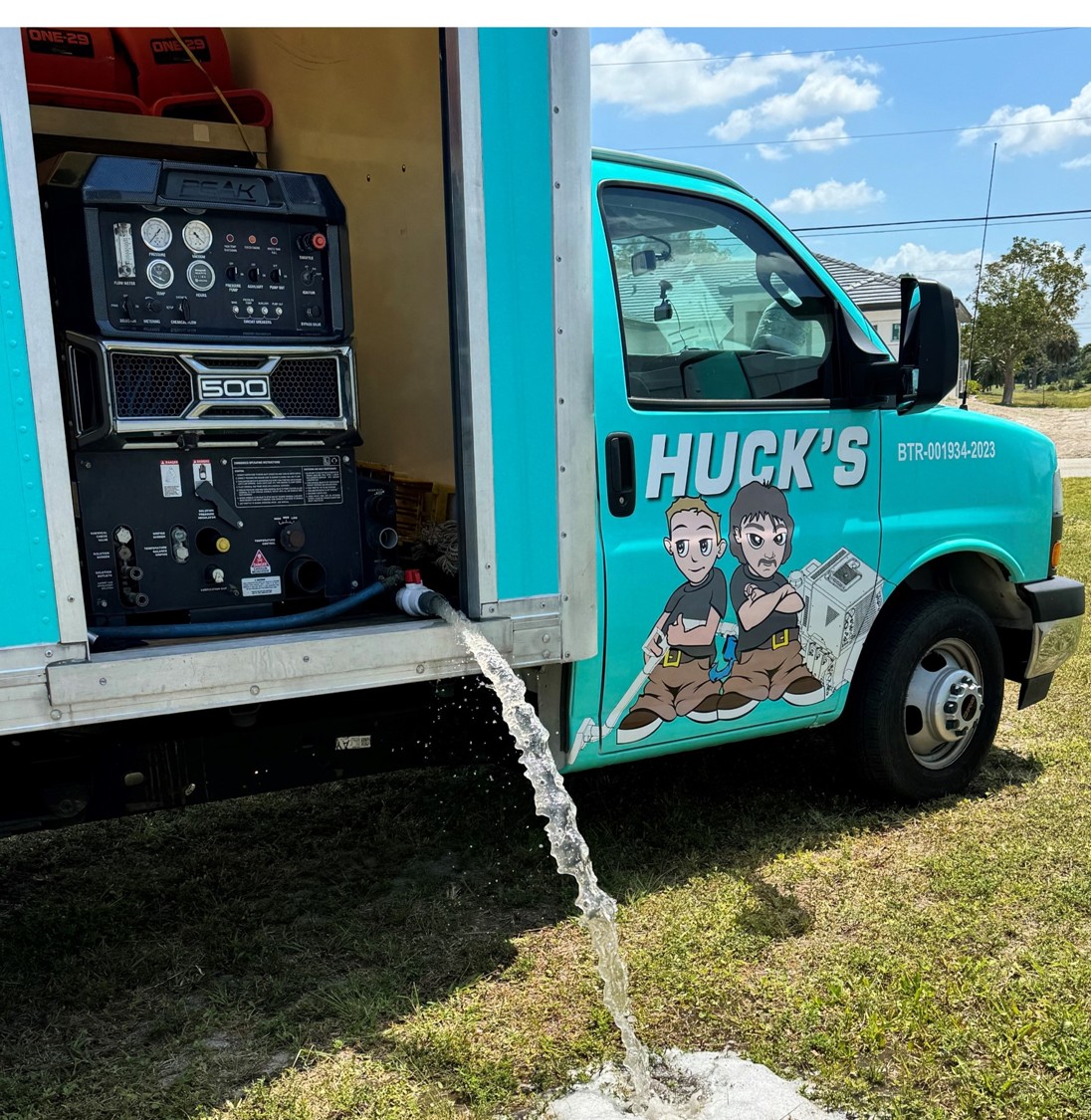 A person is using a steam cleaner on a gray couch cushion, with steam visibly rising. The background includes a yellow chair and a patterned black and white pillow on the couch.
